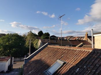 Trees and houses against sky in city