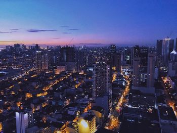 High angle view of illuminated city buildings against sky at dusk