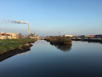 Buildings by river against sky in city