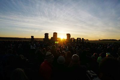 Crowd at music concert against sky during sunset