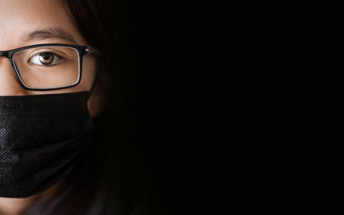 Close-up of cute girl wearing mask against black background