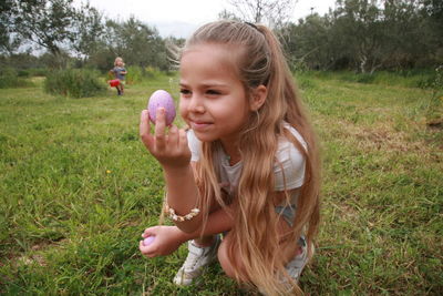 Girl looking away while standing on field ,guess what's in it