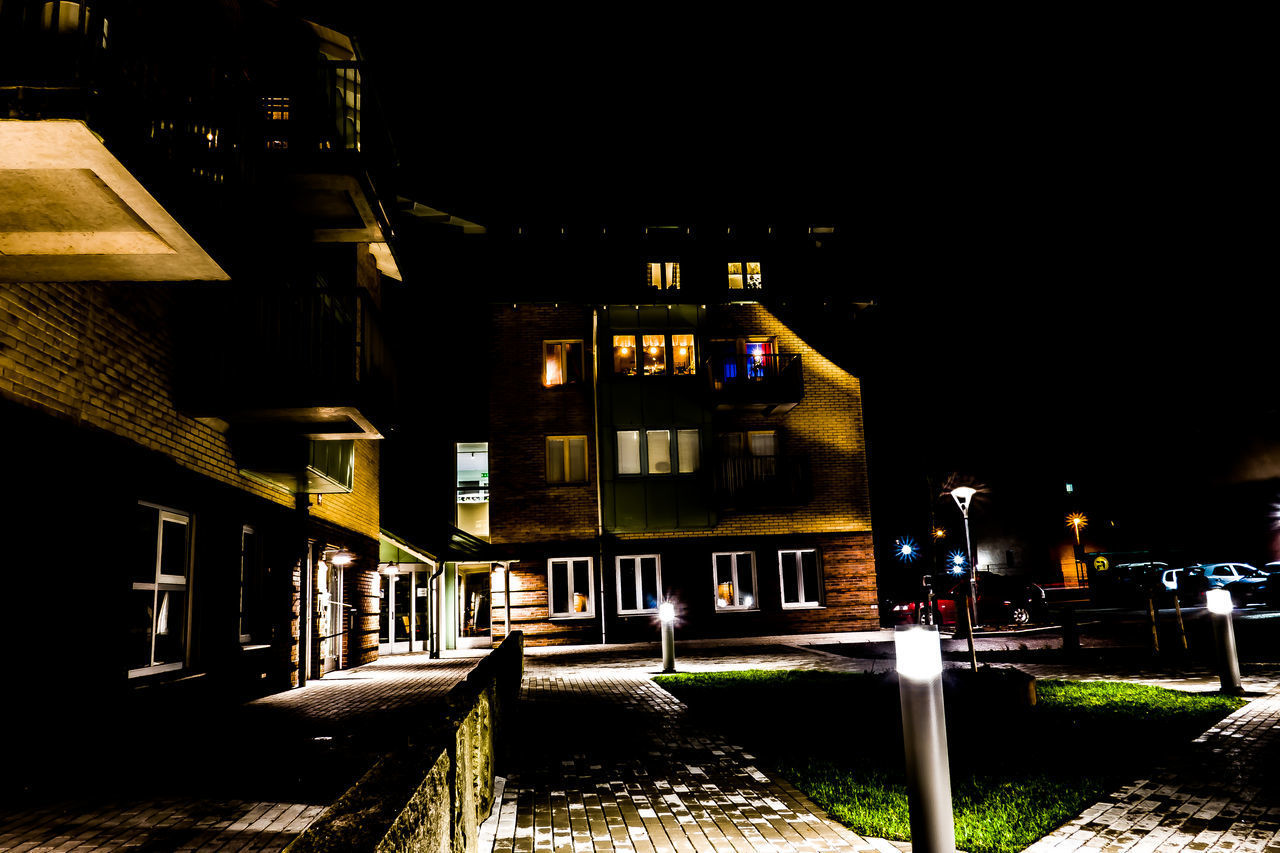 ILLUMINATED STREET AMIDST BUILDINGS AT NIGHT