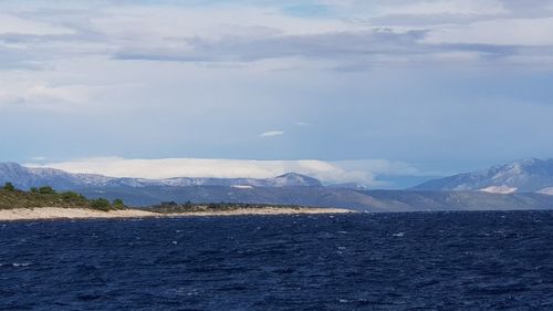 Scenic view of sea and snowcapped mountains against sky