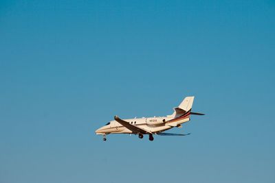 Low angle view of airplane flying against clear blue sky