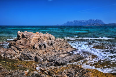 Rocks on beach against clear blue sky