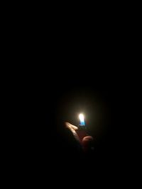 Close-up of hand holding illuminated light bulb in the dark