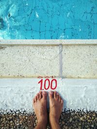 Low section of person standing by number at poolside