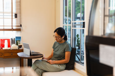 Side view of young man using laptop at home