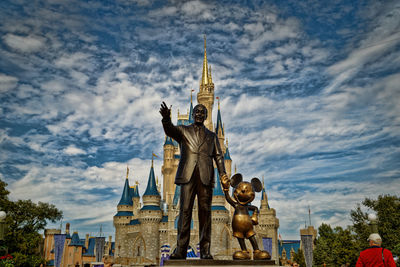 Low angle view of statue of building against cloudy sky