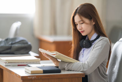 Young woman holding diary while sitting at classroom