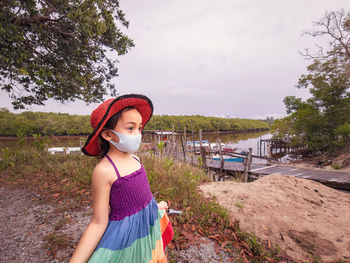 A little girl in a rainbow dress stands at the jetty. summer day.