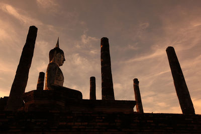 Ancient buddha statue in sukhothai historical park at sunset