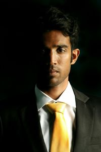 Portrait of businessman standing against black background