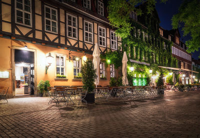 Illuminated street by buildings in town at night