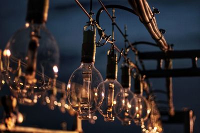 Close-up of illuminated light bulb hanging at night