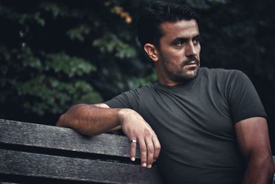 Thoughtful man looking away while sitting outdoors