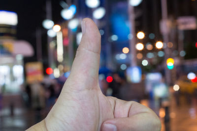 Midsection of person hand in illuminated city at night