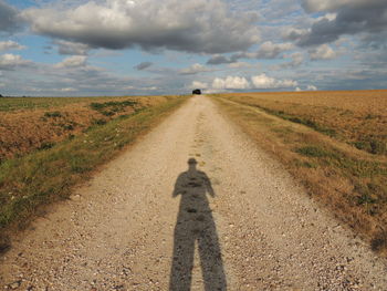 Shadow of man on dirt road