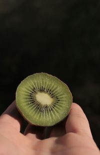 Midsection of person holding apple against black background