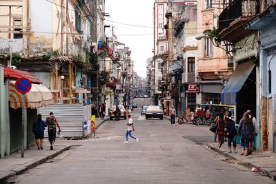 People walking on road amidst buildings in city