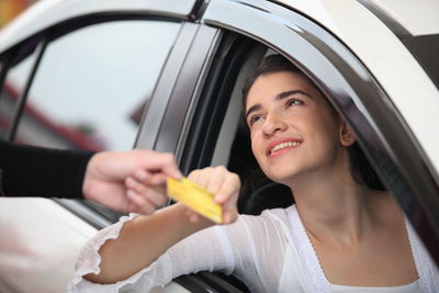 Portrait of smiling woman holding ice cream in car