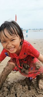 Portrait of smiling girl playing in sand on beach
