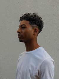 Portrait of young man looking away against wall