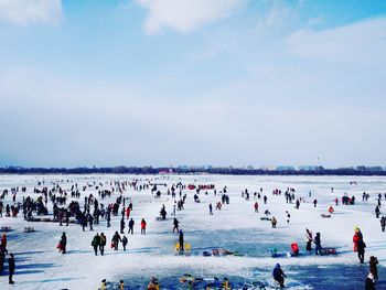 People at frozen songhua river against cloudy sky