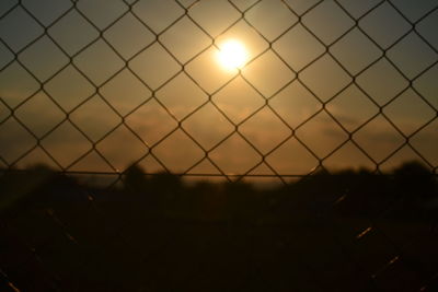 Silhouette fence against sky during sunset