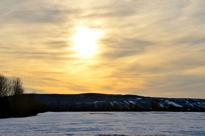 Scenic view of snow covered landscape at sunset