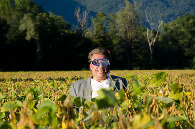 Mature man wearing swimming goggles and standing in farm