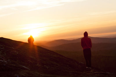 Rear view of man standing on landscape at sunset