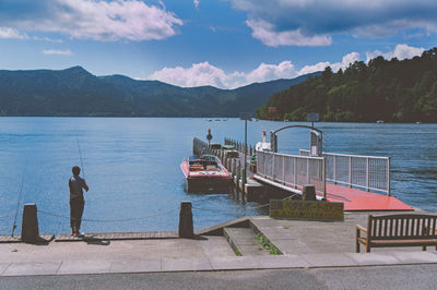 Rear view of men on boat in lake against sky