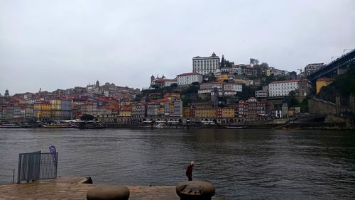 Buildings by river against sky in city