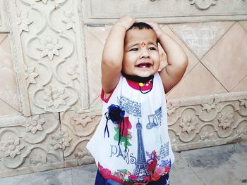 Portrait of smiling boy standing against wall