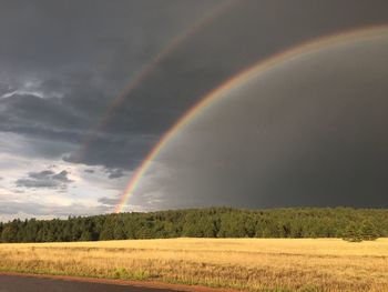 Scenic view of rainbow over field against sky