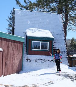 Full length of woman standing by snowcapped mountain during winter