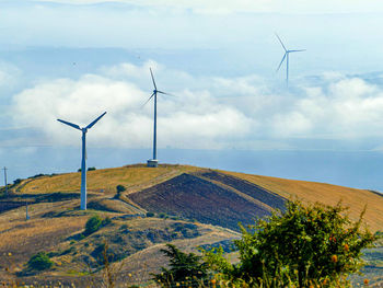 Windmill on landscape against sky