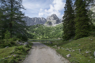 Road leading towards lake against mountains