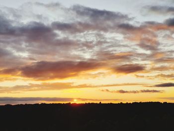 Silhouette landscape against dramatic sky during sunset