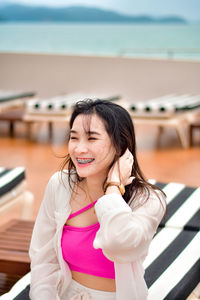 Portrait of young woman standing against railing