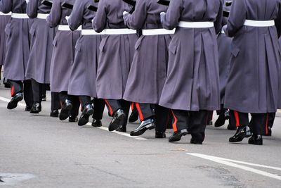 Low section of people in uniform walking on road