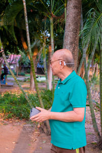 Full length of man standing by tree trunk