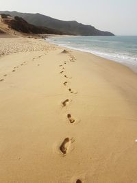 Footprints on sand at beach against sky