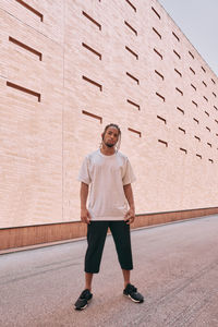 Full length portrait of young man standing against wall