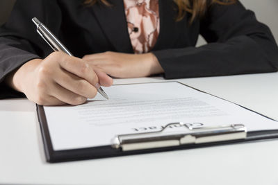 Midsection of woman reading book on table