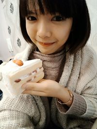 Portrait of young woman holding cake slice at home