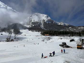 People on snowcapped mountain against sky