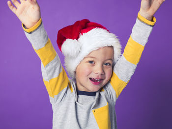 Boy wearing santa hat against purple background